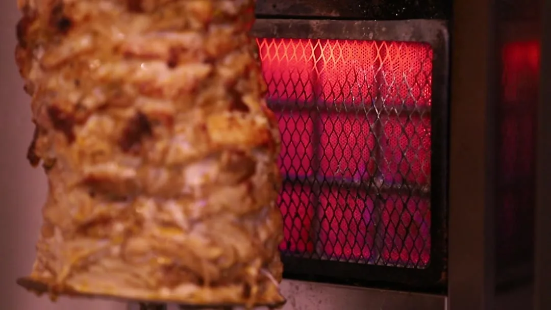 Chicken shawarma turning in front of the red heater